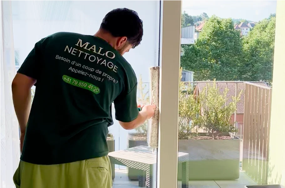 Jeune garçon nettoyant une vitre avec un produit et un racloir