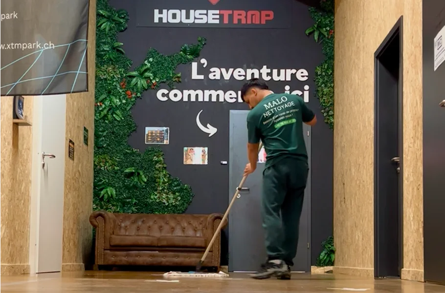 Homme de dos portant un t-shirt Malo Nettoyage passant l’aspirateur chez un particulier