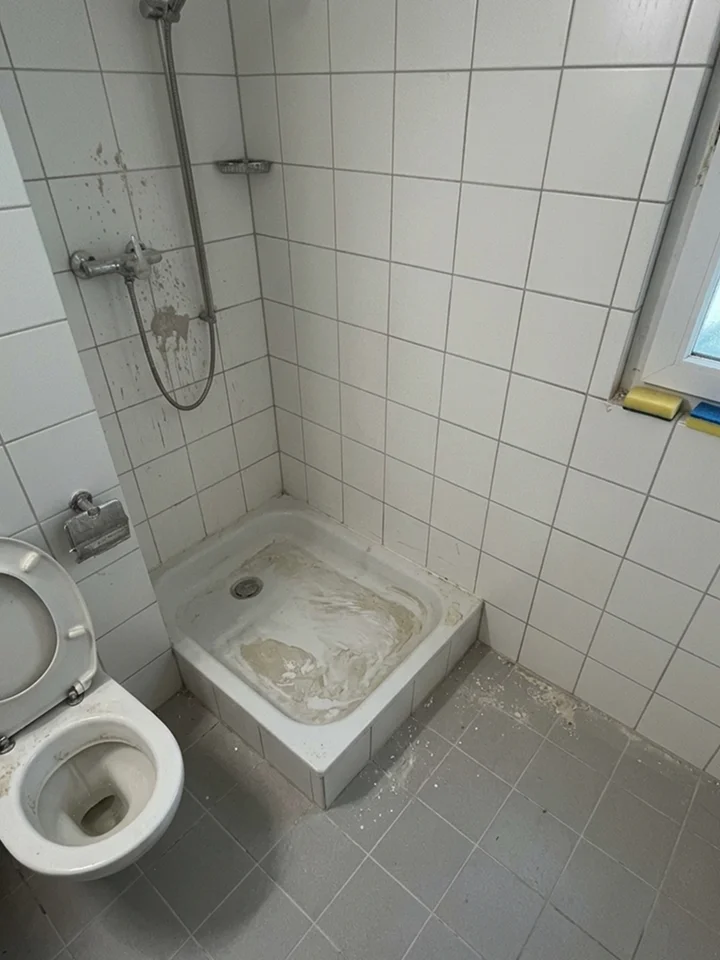 Vue avant travaux d'une salle de bain sale et négligée, avec un sol et un receveur de douche encrassés.