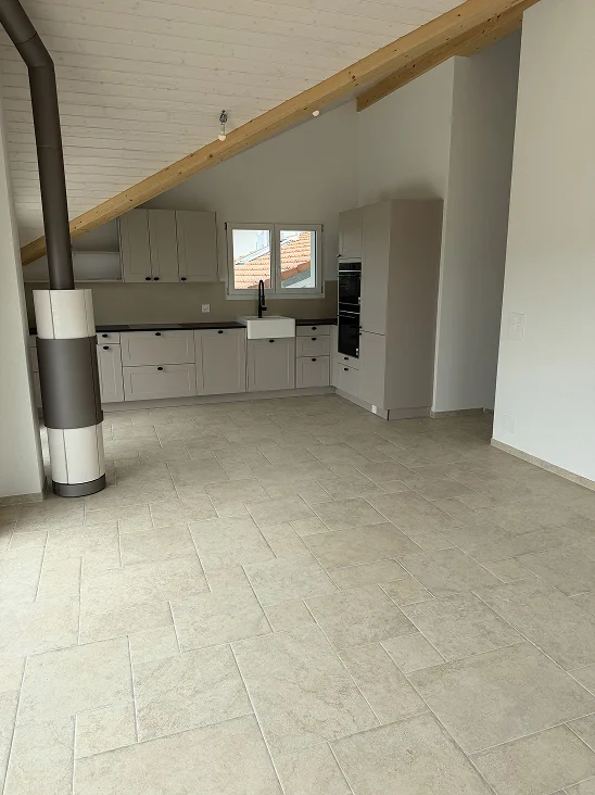 Après travaux de la même salle de bain, montrant un espace propre et rafraîchi. Sol carrelé en gris impeccable et douche brillante.